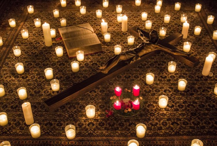 Kerzen und ein Kruzifix liegen im schummrigem Licht am Boden.
