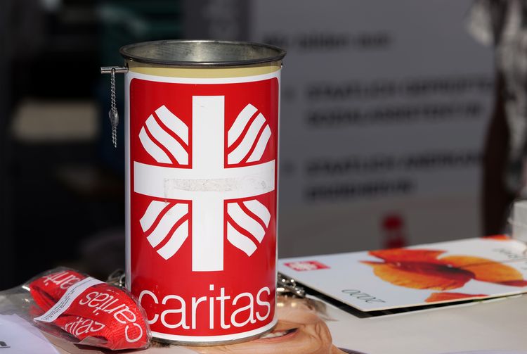 Eine Caritas-Spendendose steht auf einem Tisch.